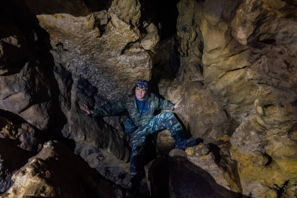 istock Man tourist in camouflage suit explores cave 1136715192