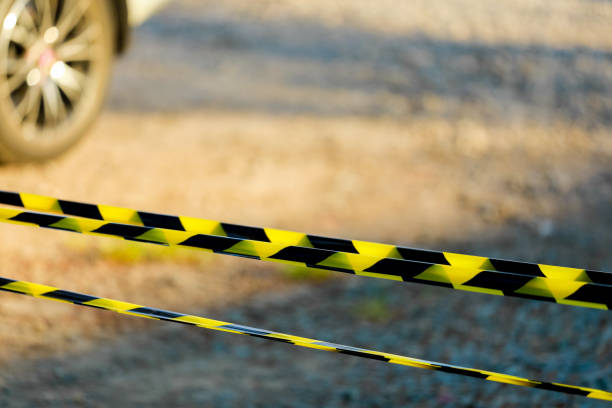 Black and yellow warning lines of barrier tape prohibit passage. Barrier on gray isolated. Cross that prohibits traffic. Danger unsafe area warning do not enter. Concept no entry. Copy space