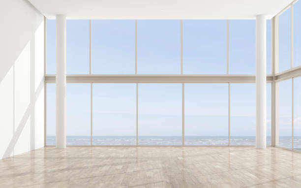 istock Architecture of white double space living room ,minimal style with laminate floor. Interior design with high glass panel system on sea view background. 3d rendering. 1136725903