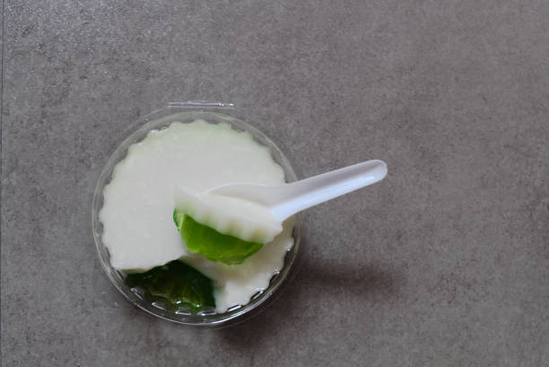 Coconut jelly in a clear plastic crate on a brown background was scooped by a white spoon.