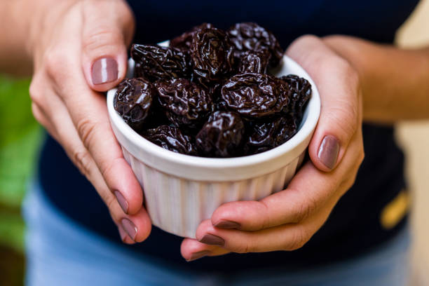 istock Hand of brunette model holding white pot with dried plum 1136727939