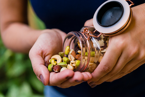 Brunette model hand holding glass hermetic pot with mix of nuts