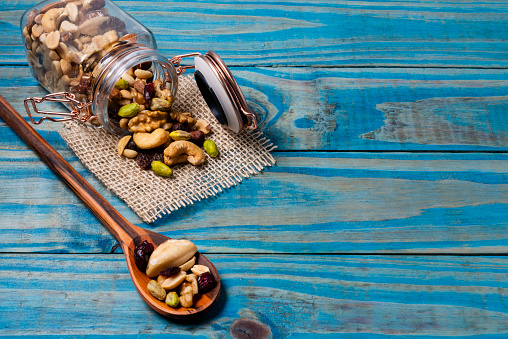 Hermetic jar of glass with mix of nuts on blue wooden table.