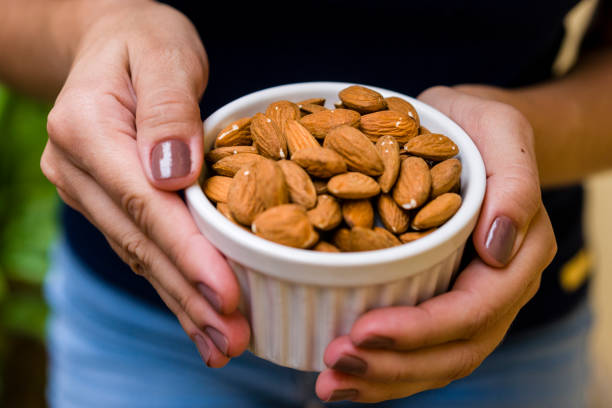 istock Hand of brunette model holding white pot with natural almonds 1136728816