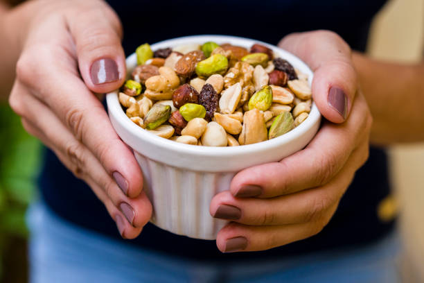 istock Brunette model hand holding white pot with mix of nuts 1136728911