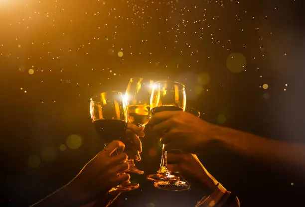 Clink Glasses at night party celebration friends group golden tone, Hands holding wine for event festival.