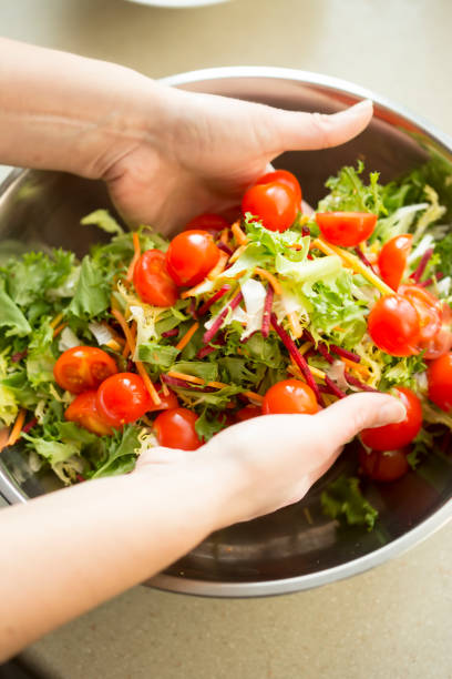 istock Hands mixing mixed leaves with tomatoes salad preparation 1136735392