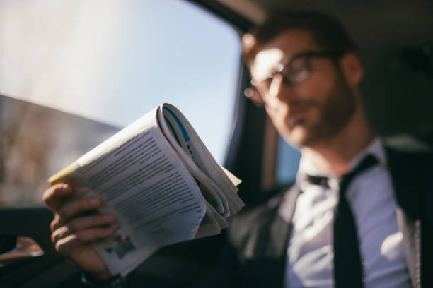 uomo d'affari in auto a leggere il giornale - newspaper reading holding paper foto e immagini stock