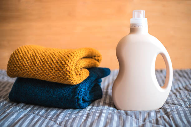 botella de detergente y una pila de suéteres. - liquid soap blue plastic textile fotografías e imágenes de stock