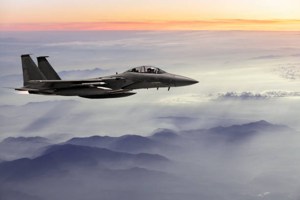 f-15 fighter jet fliegt bei sonnenuntergang - f15 stock-fotos und bilder