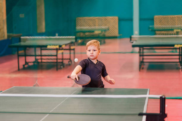 Caucasian boy seven years old playing table tennis indoors