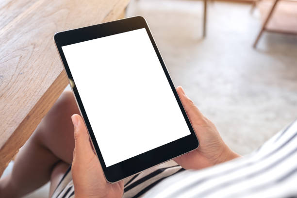 istock a woman sitting and holding black tablet pc with blank white desktop screen 1136747952