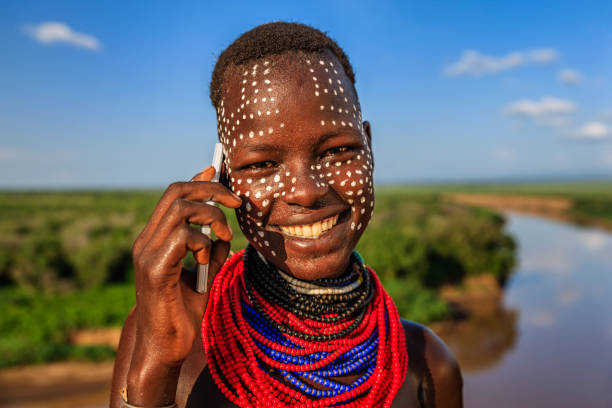 Young girl from Karo tribe using a smart phone, Ethiopia, Africa The Karo tribe is a tribe that lives in the southwestern region of the Omo Valley near Kenya, Africa. They are largely pastoralists. omo river photos stock pictures, royalty-free photos & images