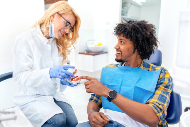 стоматолог, показывающий модель челюстей пациенту в стоматологической клинике - smiling dentist office dentists chair women стоковые фото и изображения
