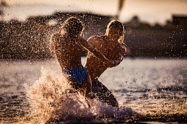 istock Playful couple having fun while spinning in the sea at sunset. 1136750164