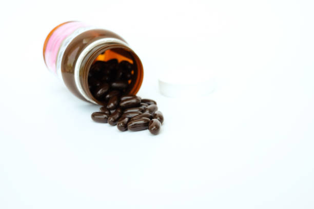 istock black capsule poring off the bottle on white background 1136752647