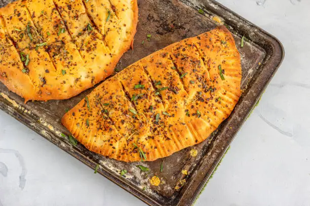Stuffed Garlic Bread with Cheese, Bell Peppers and Herbs on a Baking Tin Horizontal Photo. Garlic Bread Photography Directly from Above.