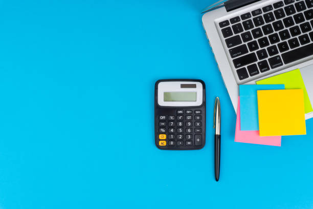 istock Workspace with calculator, black pen, laptop on the turqoise blue background 1136757473