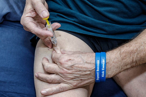 Post-Surgery Cancer Patient Self Injecting Blood Thinner Medication A real person real life senior adult man post-surgery cancer patient is self injecting blood thinner medication with a medical equipment disposable one-use syringe as a precaution to prevent blood clots. He was required to do this every day during the month following his recent colorectal cancer surgical procedure. He has very dry skin, and there are several bruises showing on both thighs from earlier injections. Another day in the life of a cancer patient. Part of a "Daily Living with Cancer" imaged series - submitted toward brief #775310942. hand thigh stock pictures, royalty-free photos & images