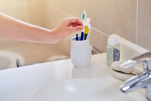 Closeup shot of a woman using a toothbrush in a holder in a bathroom at home