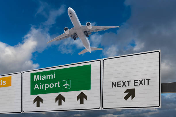 Road sign indicating the direction of Miami airport and a plane that just got up. Road sign indicating the direction of Miami airport and a plane that just got up. landing craft stock pictures, royalty-free photos & images