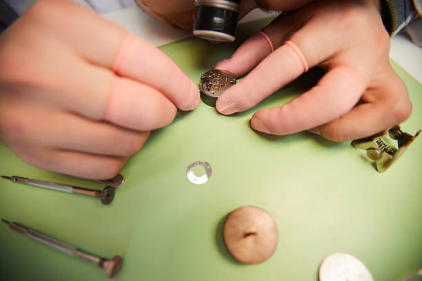 istock Close-up of unrecognizable worker in monocular magnifying loupe on eye working on small gear of mechanical watch 1136773508