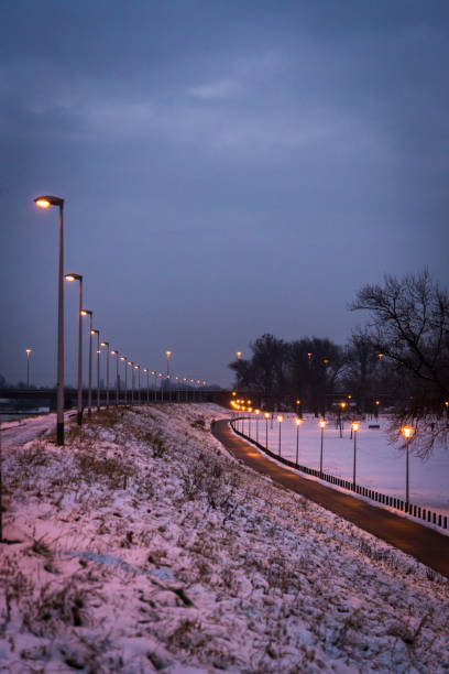 Lit up street lamps and path in snow at dusk, Zagreb, Croatia