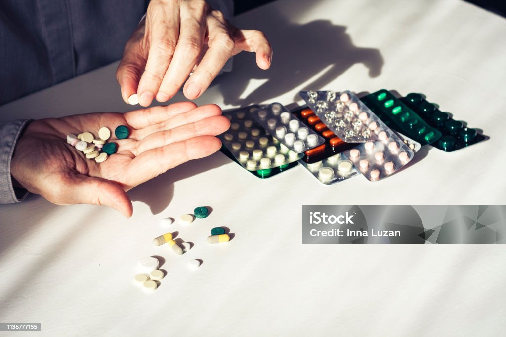 Medicine pills or capsules with old woman"u2019s hands on white background with copy space. Blister pack Capsule - Medicine Stock Photo