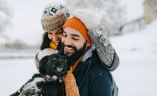 Couple in the snow play with dog
