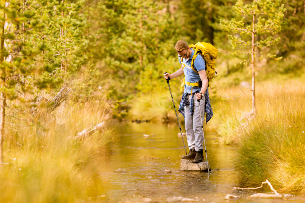 istock Young man crosses a mountain stream on a sunny day 1136778492
