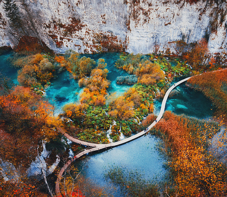 Beautiful view with wooden trekking path, autumn colors trees, lakes and waterfall landscape in Plitvice Lakes in Croatia