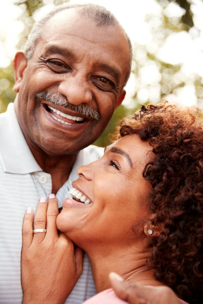 istock Senior black man and his middled aged daughter embracing and laughing, vertical 1136780384