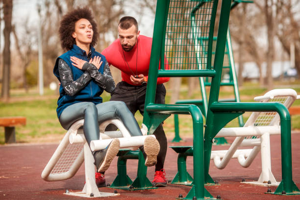 istock Young athletic woman doing sit-ups exercise on a sit up bench in a public park while per personal trainer is encouraging her and monitoring her time on a stopwatch 1136780763