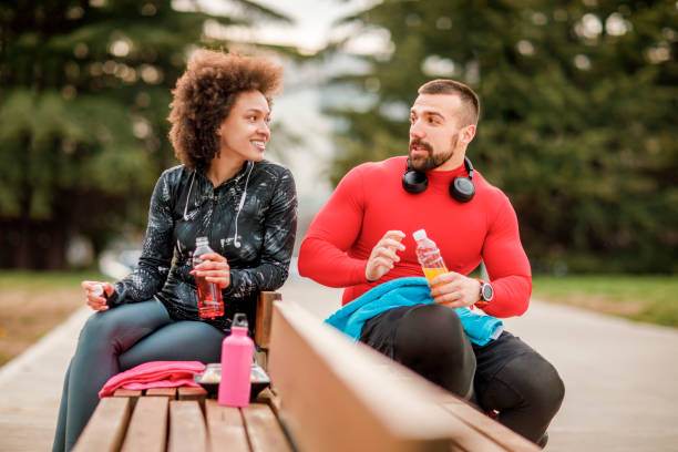 istock Young athletic female hydrating herself while taking a break with her friend after exercising in a park 1136781143