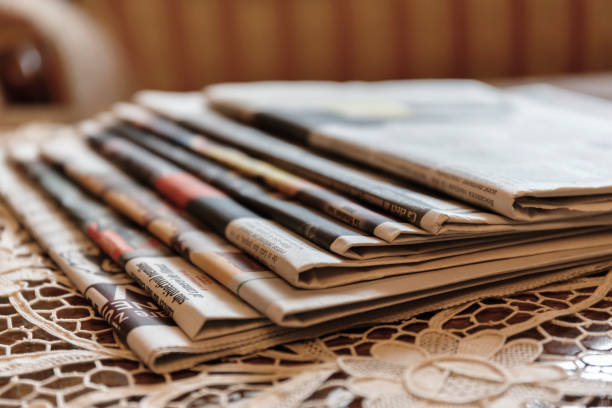 Several newspapers laid on vintage white work lace tablecloth stock photo