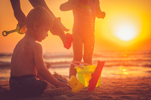 Little boy and girl building a sandcastle on the beach  in summer