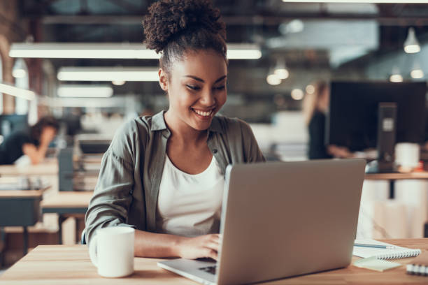 istock Beautiful afro american lady working on laptop in modern office 1136789035