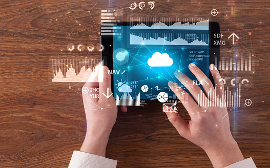 Hand holding tablet and checking finantial report on cloud computing system