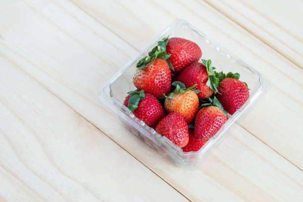 istock Fresh red strawberries in plastic container with wooden background 1136792627