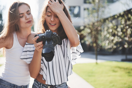 Two pretty pretty friends of the girl with the camera take photos together and walk in the city.