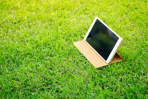 Digital tablet on green grass