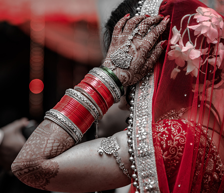 Beautiful Indian Bride in traditional hindu wedding attire with lehnga, bridal bangles and shy pose