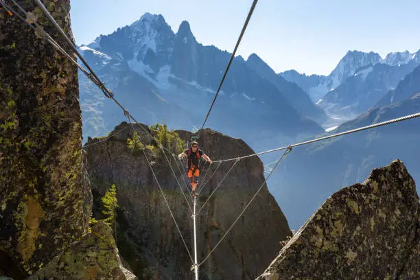 Photo of Mountaineer crossing cable bridge via ferrata, Chamonix France.