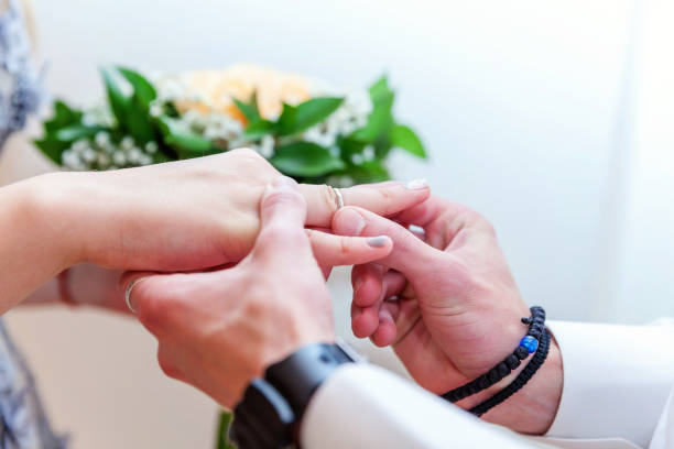 istock Groom hand putting wedding ring on bride finger 1136797912