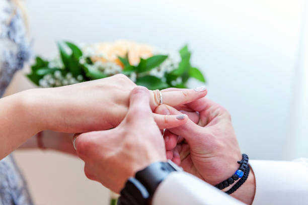 istock Groom hand putting wedding ring on bride finger 1136797933