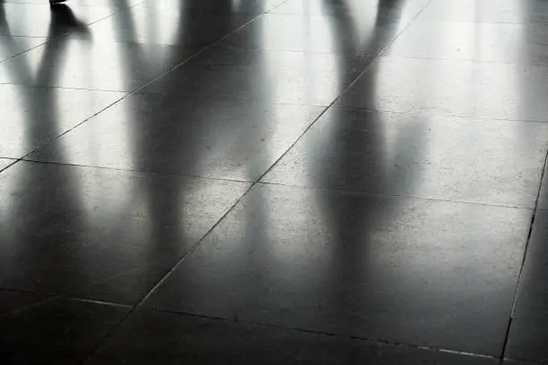 Photo of Dark shadows of walking people on the floor