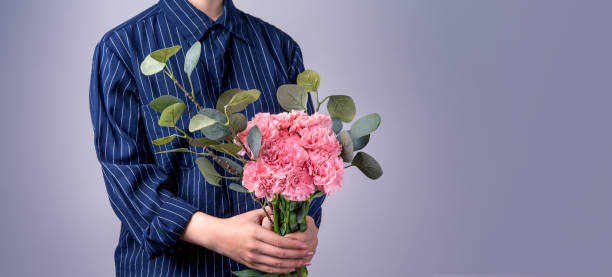 母親の日の概念のための贈り物として手作りの美しい開花ベビーピンクのカーネーションの束を与える濃い青色の縞模様のシャツの若い女の子、クローズアップ、コピースペース、クリッピ� - carnation mothers day florist flower ストックフォトと画像