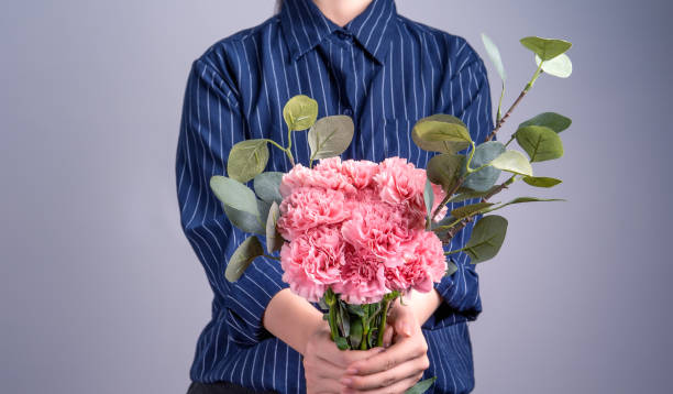 母親の日の概念のための贈り物として手作りの美しい開花ベビーピンクのカーネーションの束を与える濃い青色の縞模様のシャツの若い女の子、クローズアップ、コピースペース、クリッピ� - carnation mothers day florist flower ストックフォトと画像