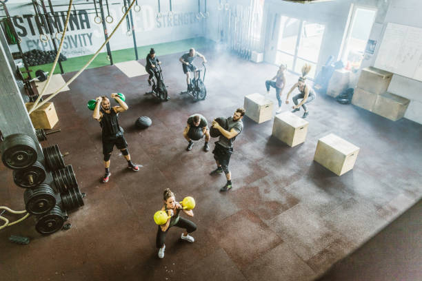 Above view of athletic people having gym training in a gym High angle view of large group of athletes exercising strength of cross training in a gym. circuit training stock pictures, royalty-free photos & images