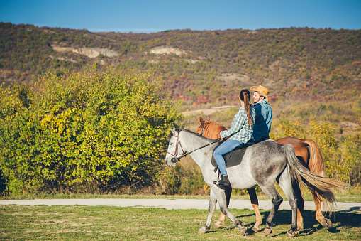 Young caucasian couple riding horses together.